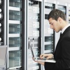 businessman with laptop in network server room